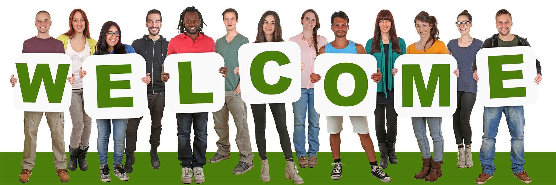 Bild zeigt eine Gruppe Menschen mit einem Schild Welcome