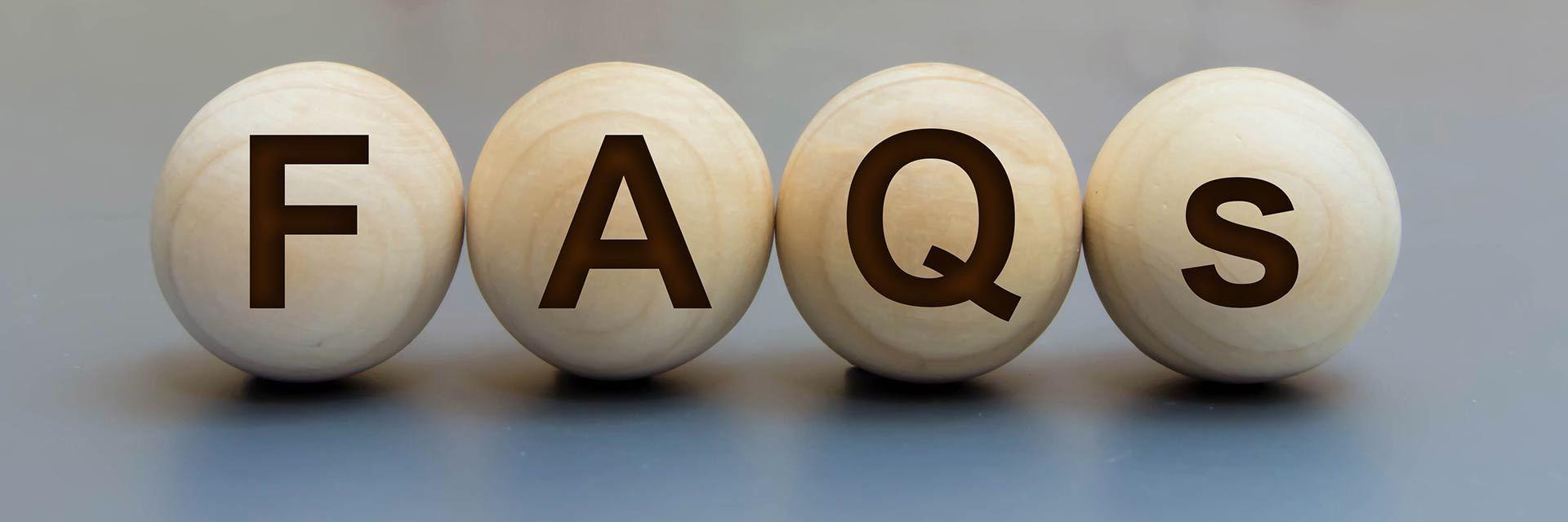 Bild zeigt vier Holzkigeln mit der Aufschrift FAQs